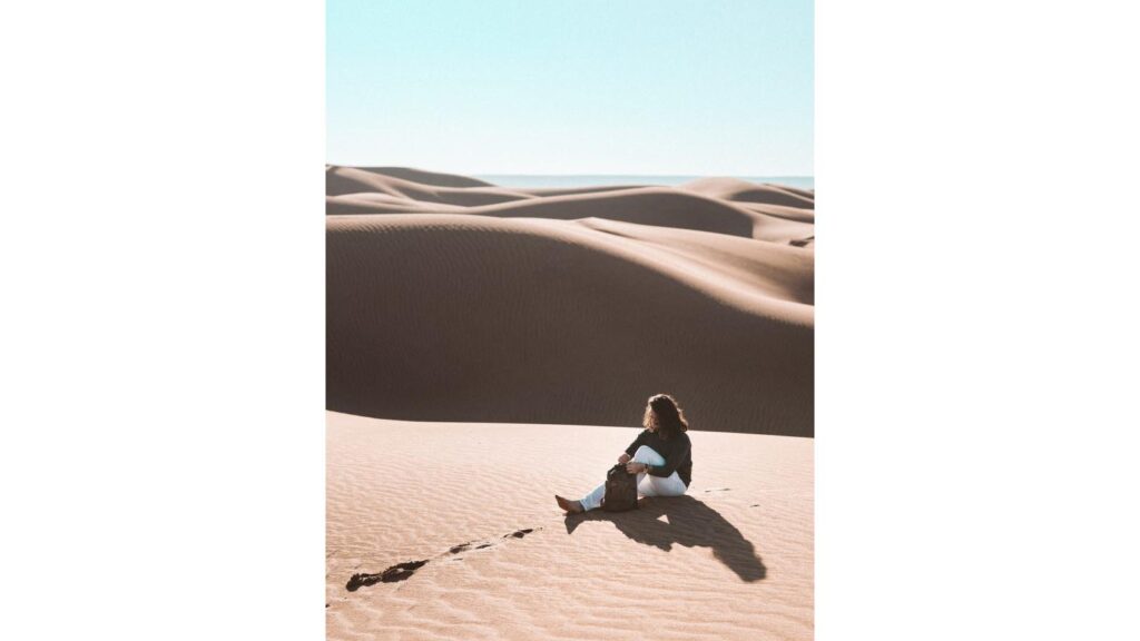 woman-in-white-long-sleeve-shirt-sitting-on-brown-sand-4405254-683×1024